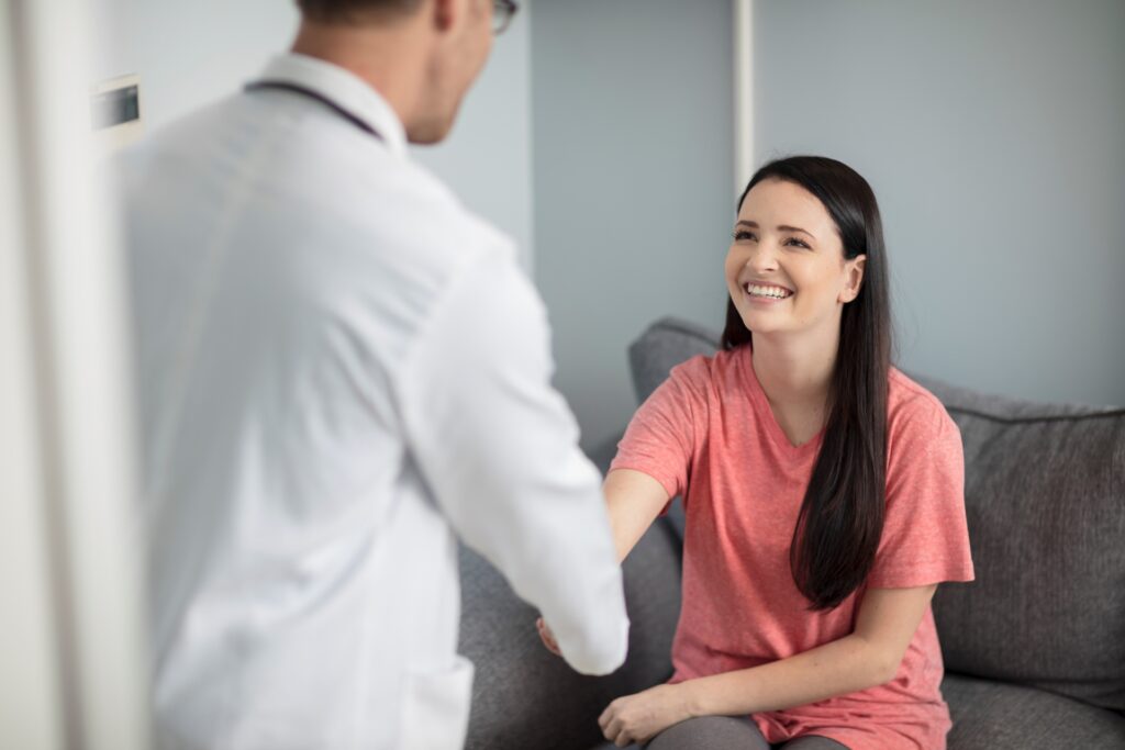 female patient smiling shaking the male doctors hand