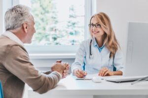 Male patient sitting at across from a doctor at a desk smiling and getting paperwork