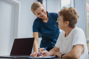 Smiling patient filling out feedback with smiling nurse